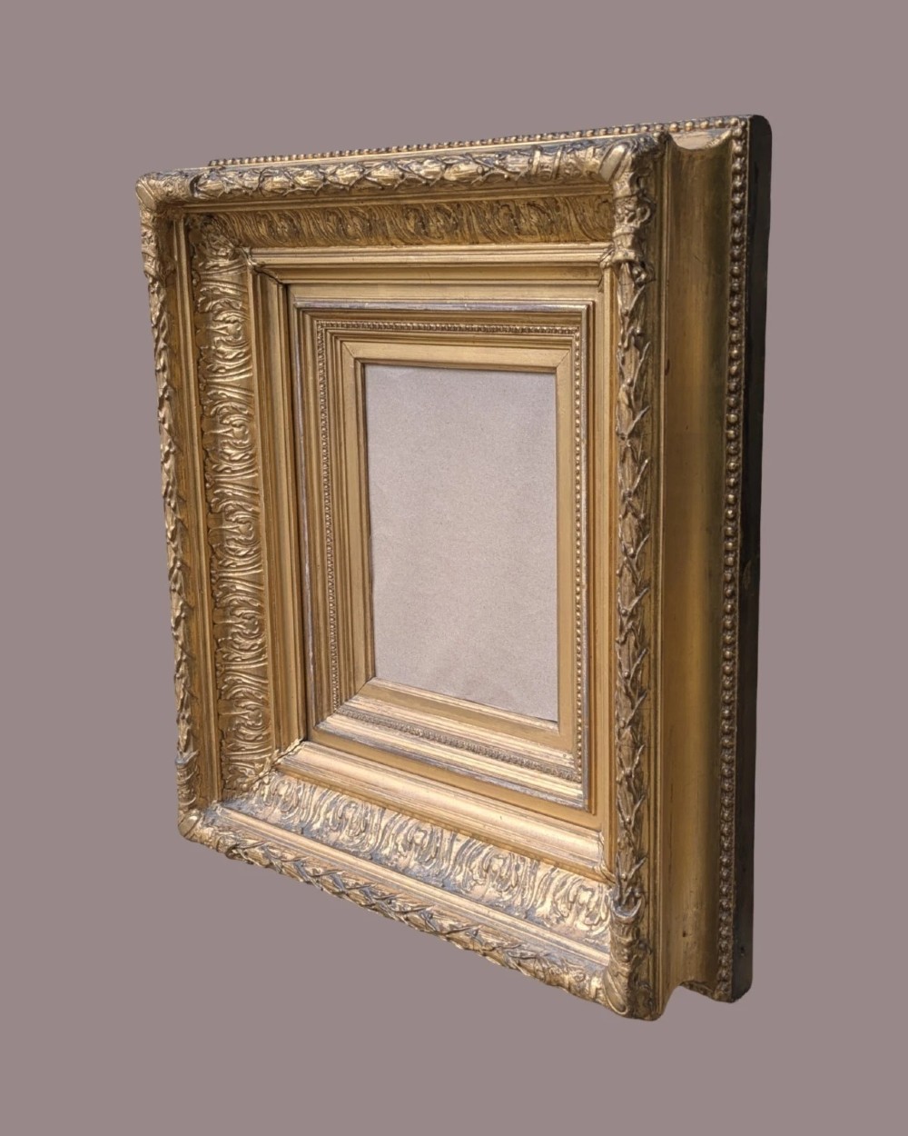 A matching pair of deep profile Victorian gilt picture frames featuring layered cove moulding and carved leaf border details. View IV