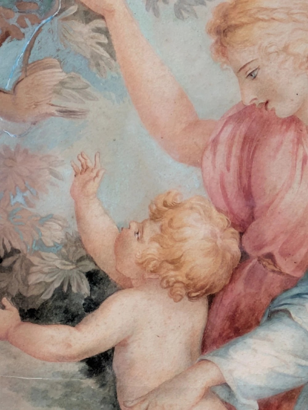 A framed classical watercolour painting depicting two draped female figures and a child beneath trees, presented in a moulded gilt frame. View IV