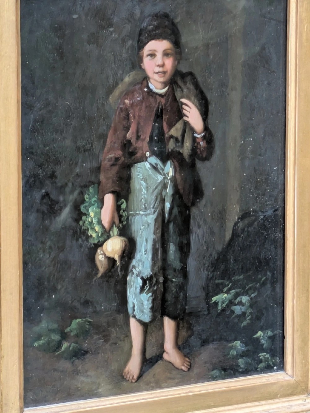 A pair of 19th-century oil paintings depicting young boys in rustic attire, mounted within deep, ornate gilded wooden frames. View VII
