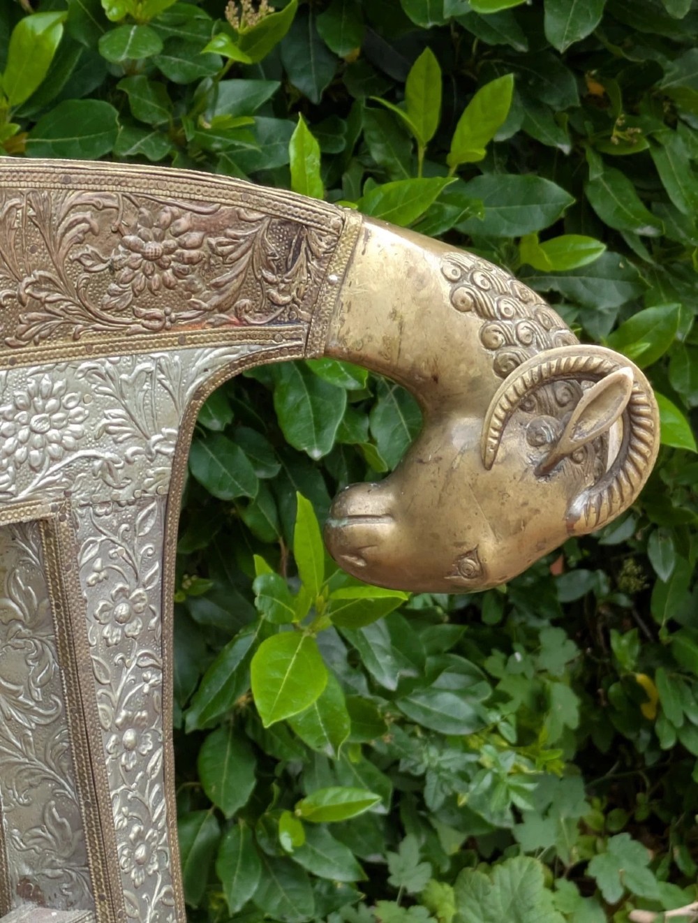 An Indian ceremonial chair wrapped in embossed silver metal with sculpted rams head terminals and a red velvet upholstered seat. View VI
