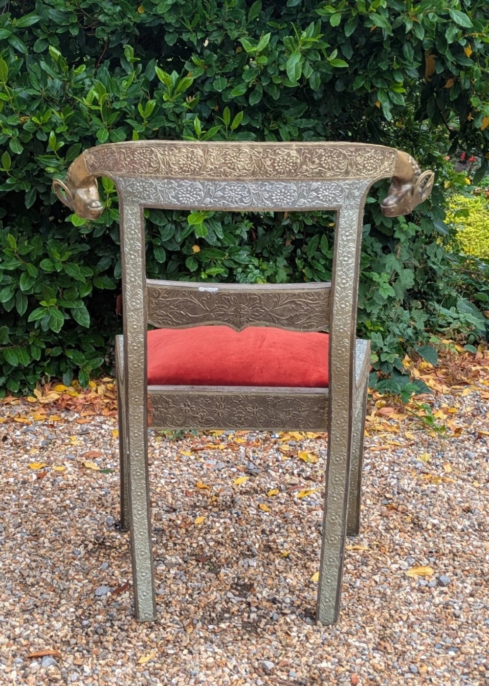 An Indian ceremonial chair wrapped in embossed silver metal with sculpted rams head terminals and a red velvet upholstered seat. View VIII