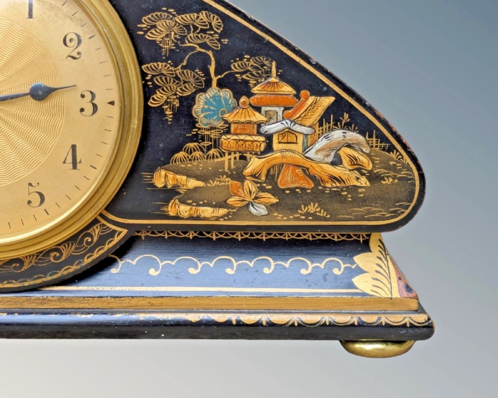 A black lacquered arched mantel clock featuring hand-painted gold Chinoiserie figures and landscapes surrounding a central brass dial. View II