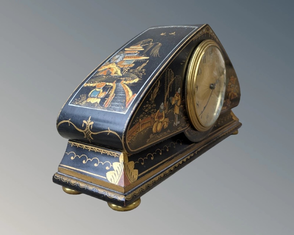 A black lacquered arched mantel clock featuring hand-painted gold Chinoiserie figures and landscapes surrounding a central brass dial. View VII