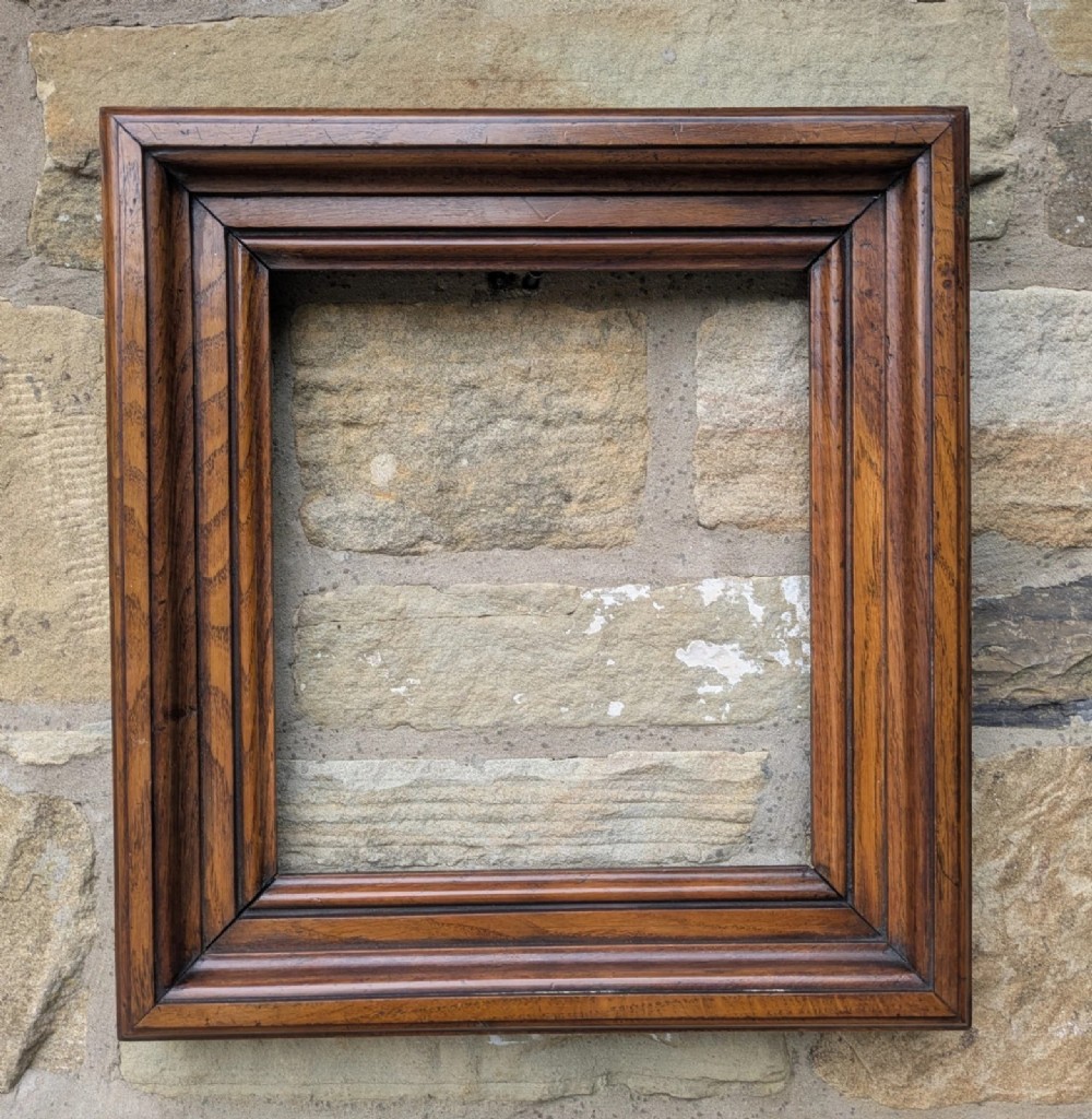 A rectangular antique solid walnut picture frame featuring multi-tiered moulding and mitred corners.