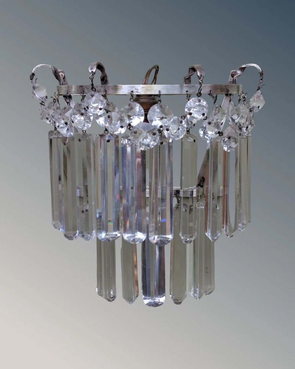 A pair of semi-circular wall lights featuring cascading tiers of clear cut crystal rectangular prisms suspended from silver-toned metal frames. View V