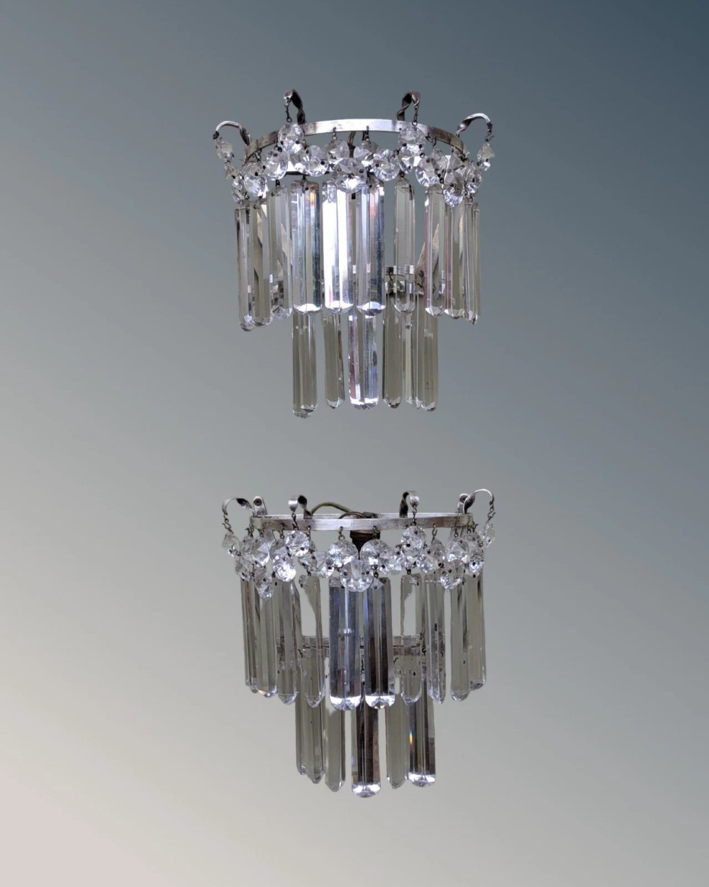 A pair of semi-circular wall lights featuring cascading tiers of clear cut crystal rectangular prisms suspended from silver-toned metal frames. View VII