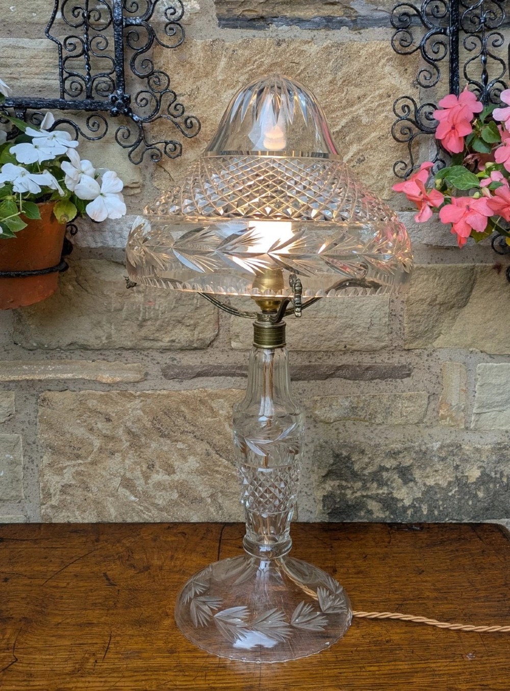 An antique cut crystal table lamp featuring a diamond-cut dome shade, a faceted baluster stem, and brass fittings. View II