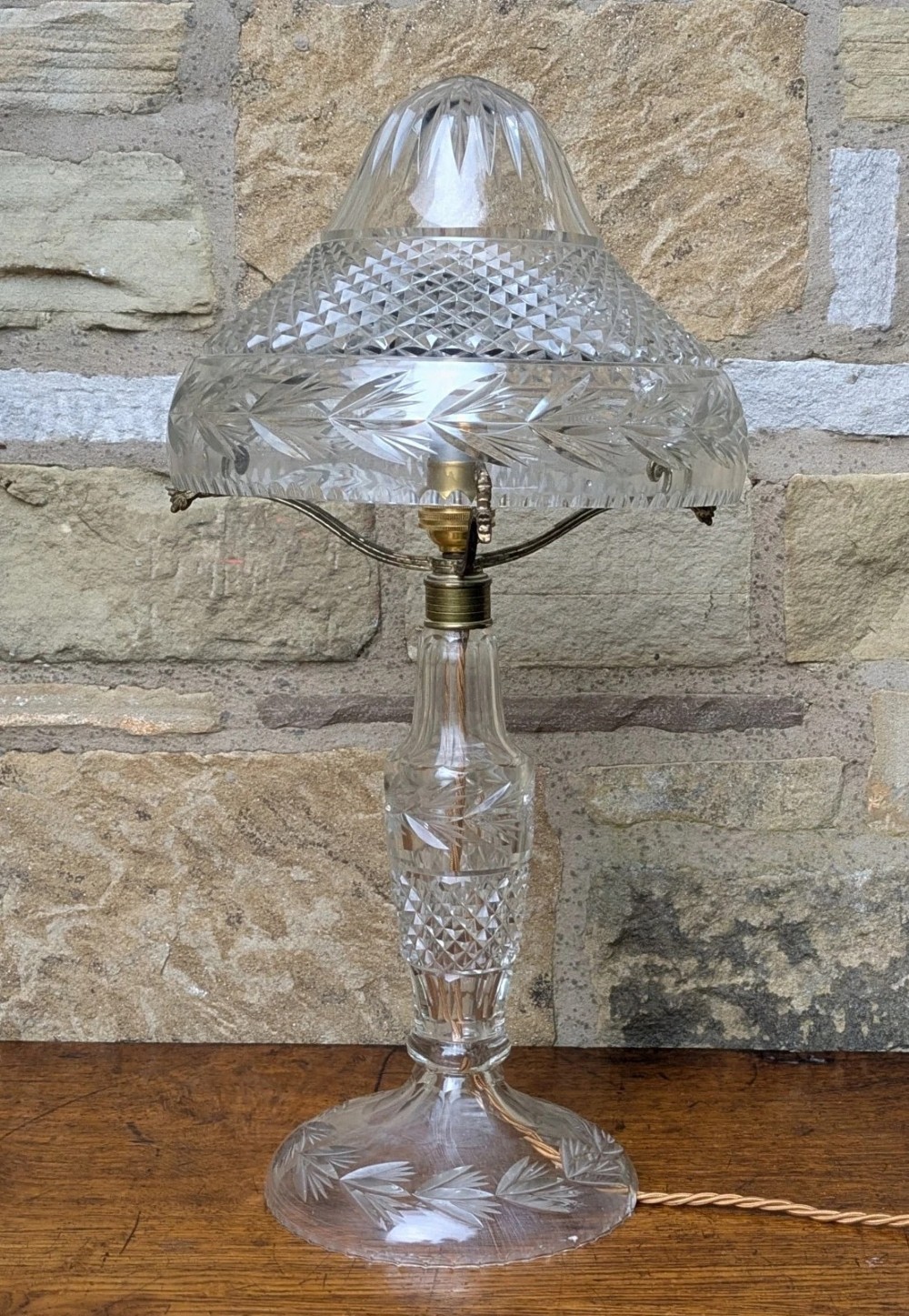 An antique cut crystal table lamp featuring a diamond-cut dome shade, a faceted baluster stem, and brass fittings. View III
