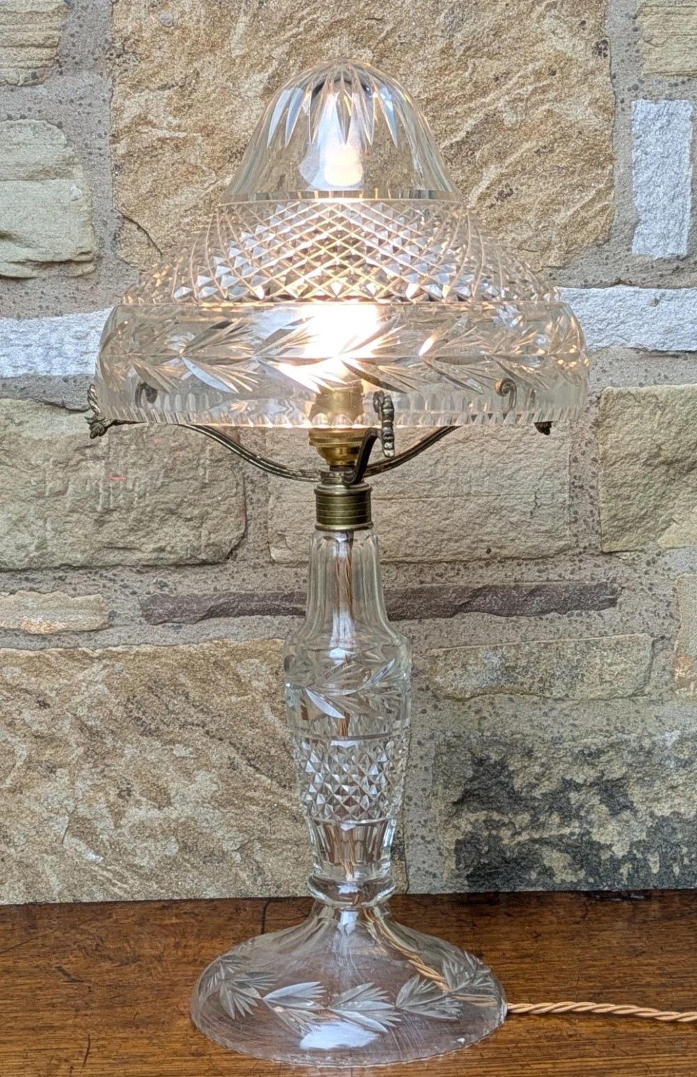 An antique cut crystal table lamp featuring a diamond-cut dome shade, a faceted baluster stem, and brass fittings. View IV