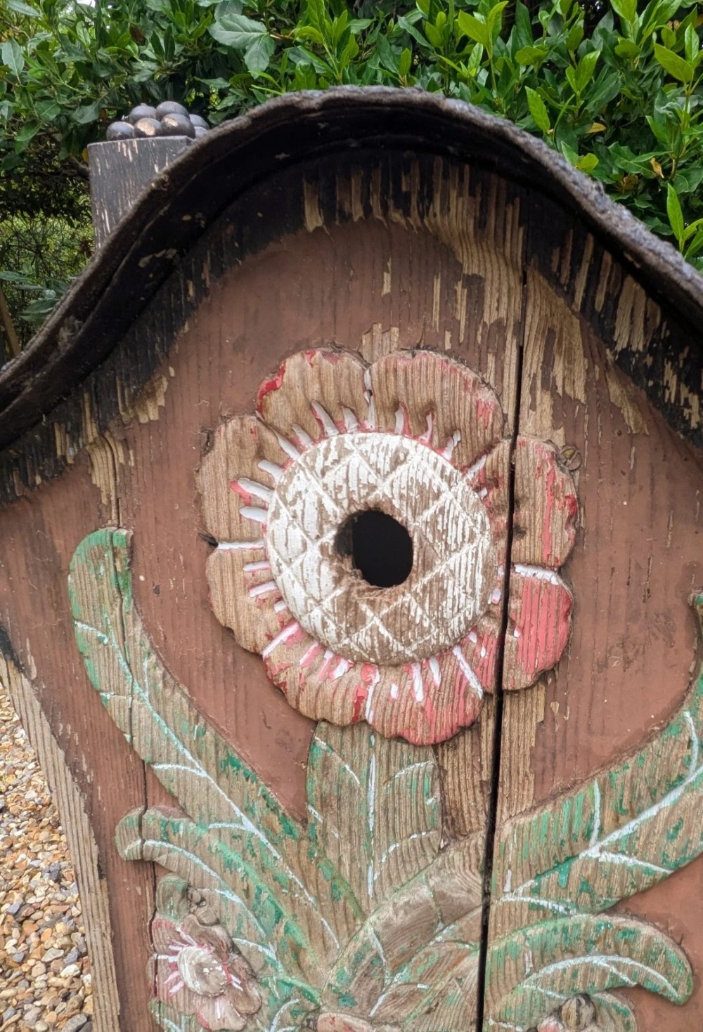 A carved and painted wooden Swedish birdhouse featuring a floral motif in a pot with a central entry hole and a chimney detail. View VIII