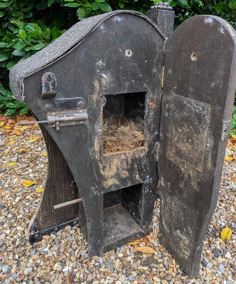 A carved and painted wooden Swedish birdhouse featuring a floral motif in a pot with a central entry hole and a chimney detail. View IX