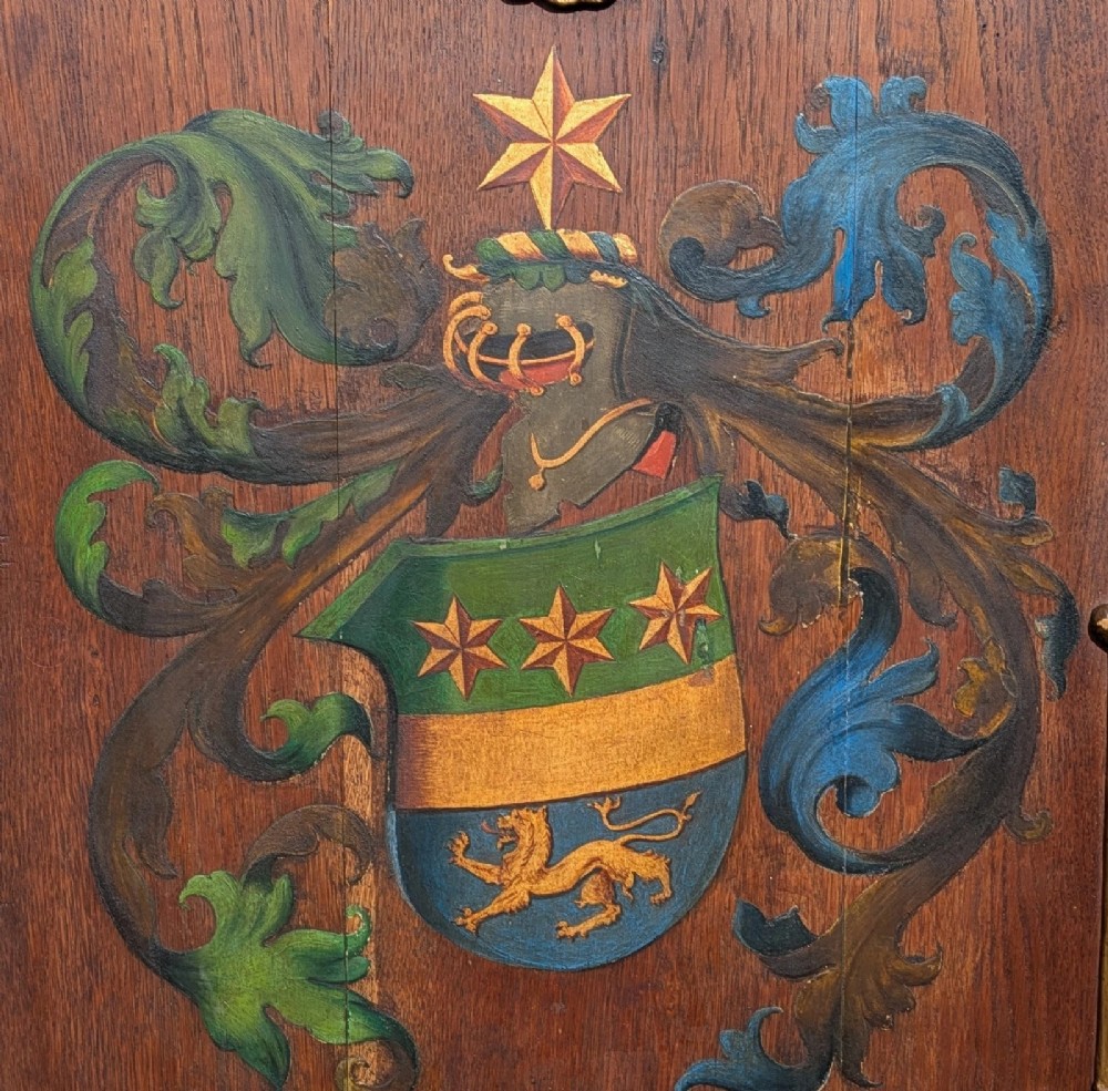 A rectangular carved oak wall plaque featuring a hand-painted heraldic coat of arms, gilt scroll moulding, and a Latin motto. View II