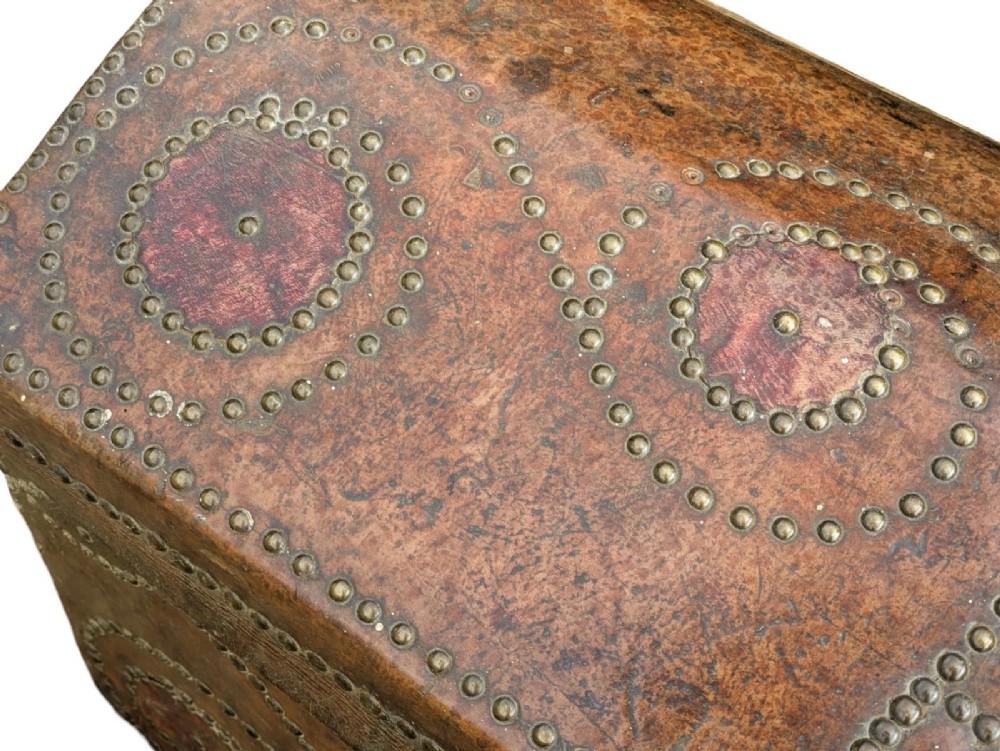 An 18th-century George II brown leather trunk embellished with decorative brass studding, iron side handles, and an open hinged lid revealing a printed floral paper interior. View VII