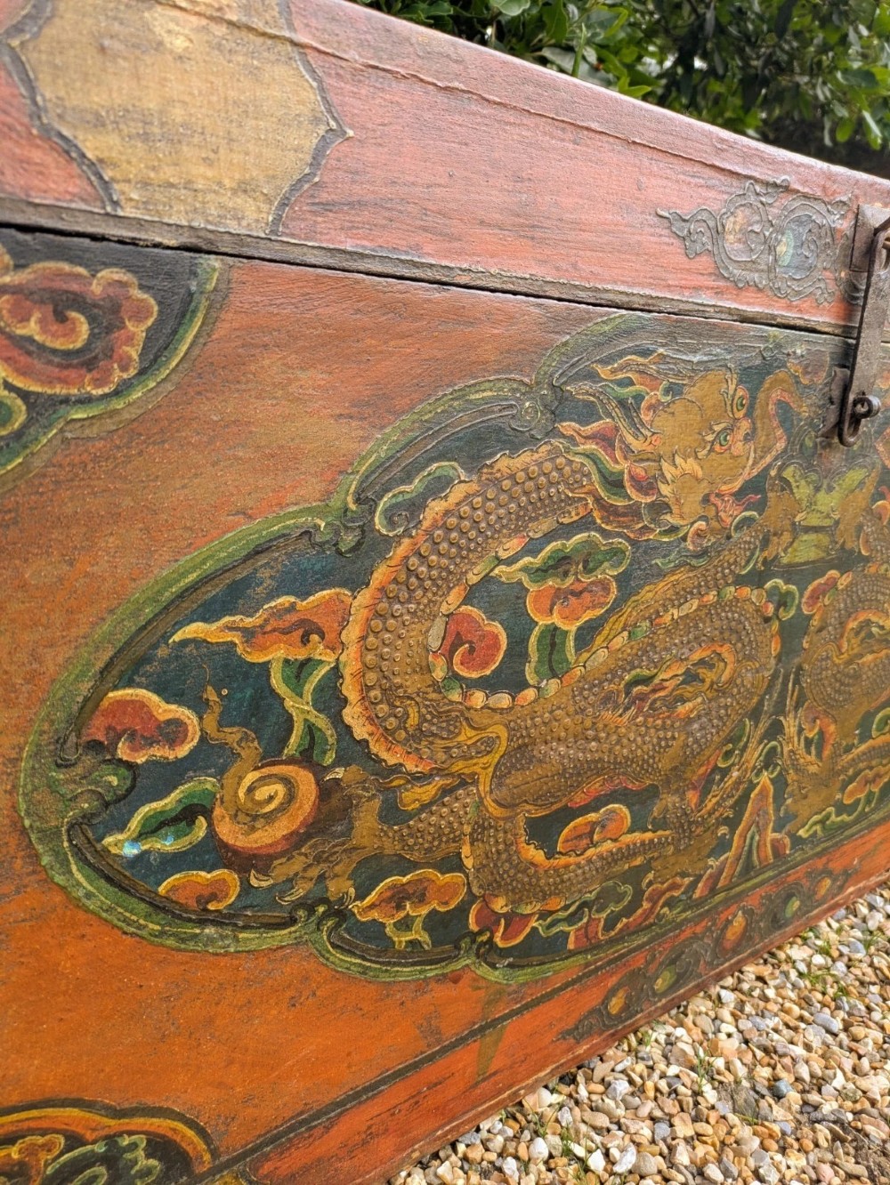 A rectangular wooden Tibetan storage chest decorated with hand-painted gold dragons on an orange ground with cloud borders and an iron latch. View III