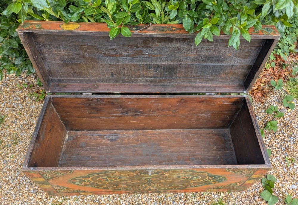 A rectangular wooden Tibetan storage chest decorated with hand-painted gold dragons on an orange ground with cloud borders and an iron latch. View IX