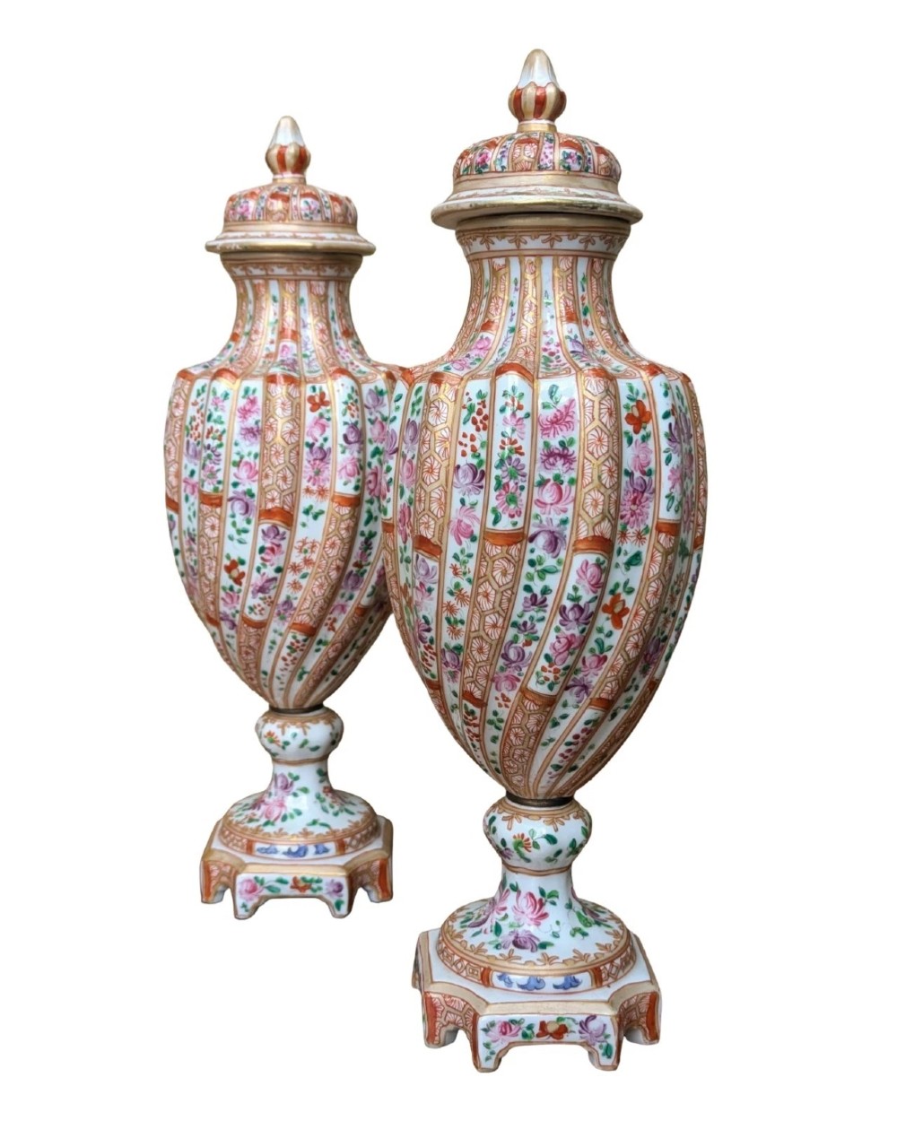 A pair of hand-painted porcelain lidded vases featuring fluted bodies, intricate floral motifs, geometric orange bands, and gilded details on square pedestals. View IX