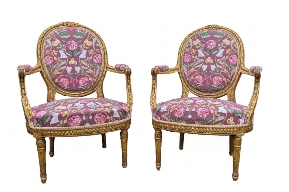 A pair of carved giltwood French armchairs featuring oval medallion backs and floral patterned plum-coloured upholstery. View II