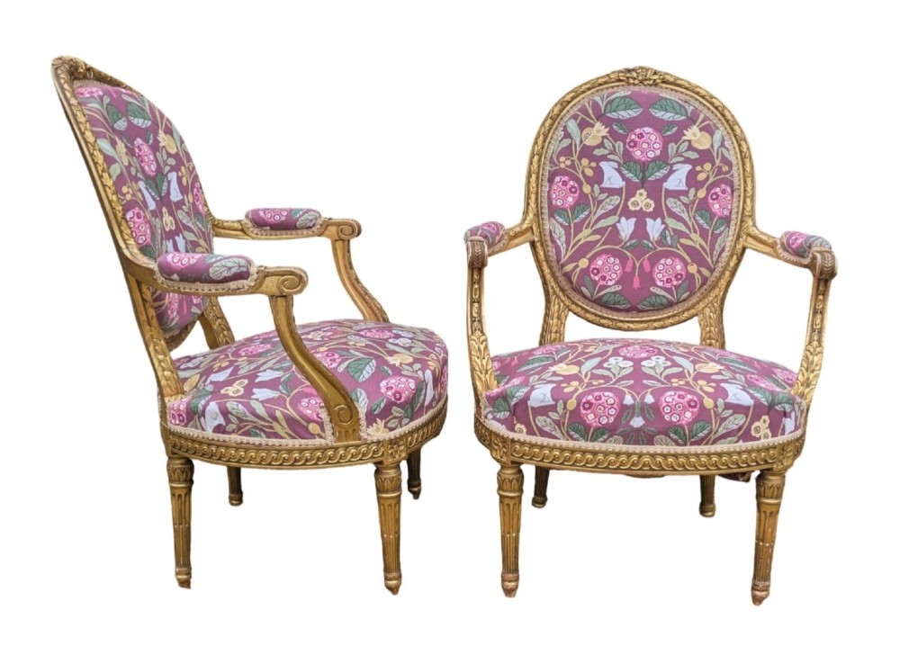 A pair of carved giltwood French armchairs featuring oval medallion backs and floral patterned plum-coloured upholstery. View III