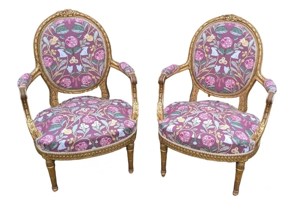 A pair of carved giltwood French armchairs featuring oval medallion backs and floral patterned plum-coloured upholstery. View VI