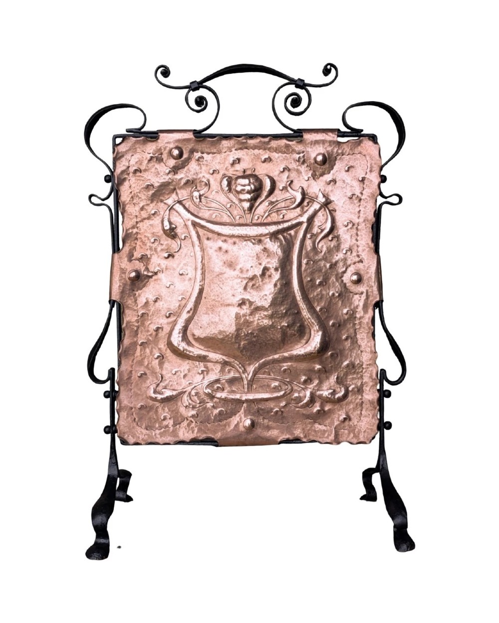 An Arts and Crafts fire screen constructed from a hand-hammered copper central panel with raised relief decoration, held within a black wrought iron scrollwork frame. View V