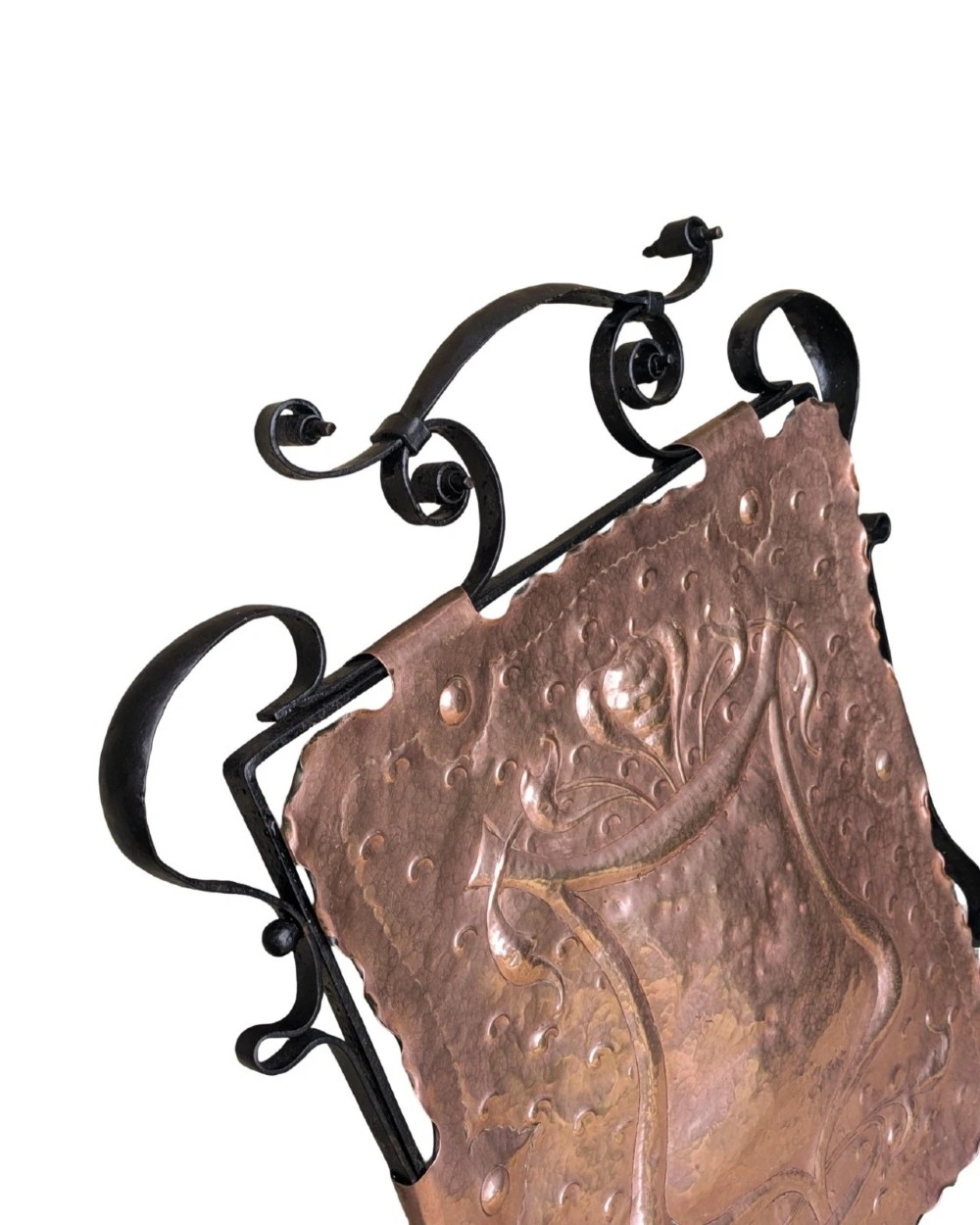 An Arts and Crafts fire screen constructed from a hand-hammered copper central panel with raised relief decoration, held within a black wrought iron scrollwork frame. View VI