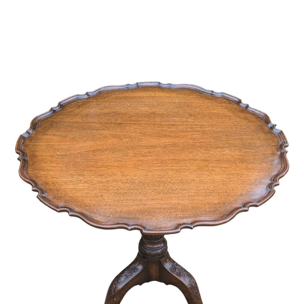 A Georgian mahogany tilt-top table with a scalloped piecrust edge shown in a raised vertical position above a turned pedestal and carved tripod cabriole legs. View IV