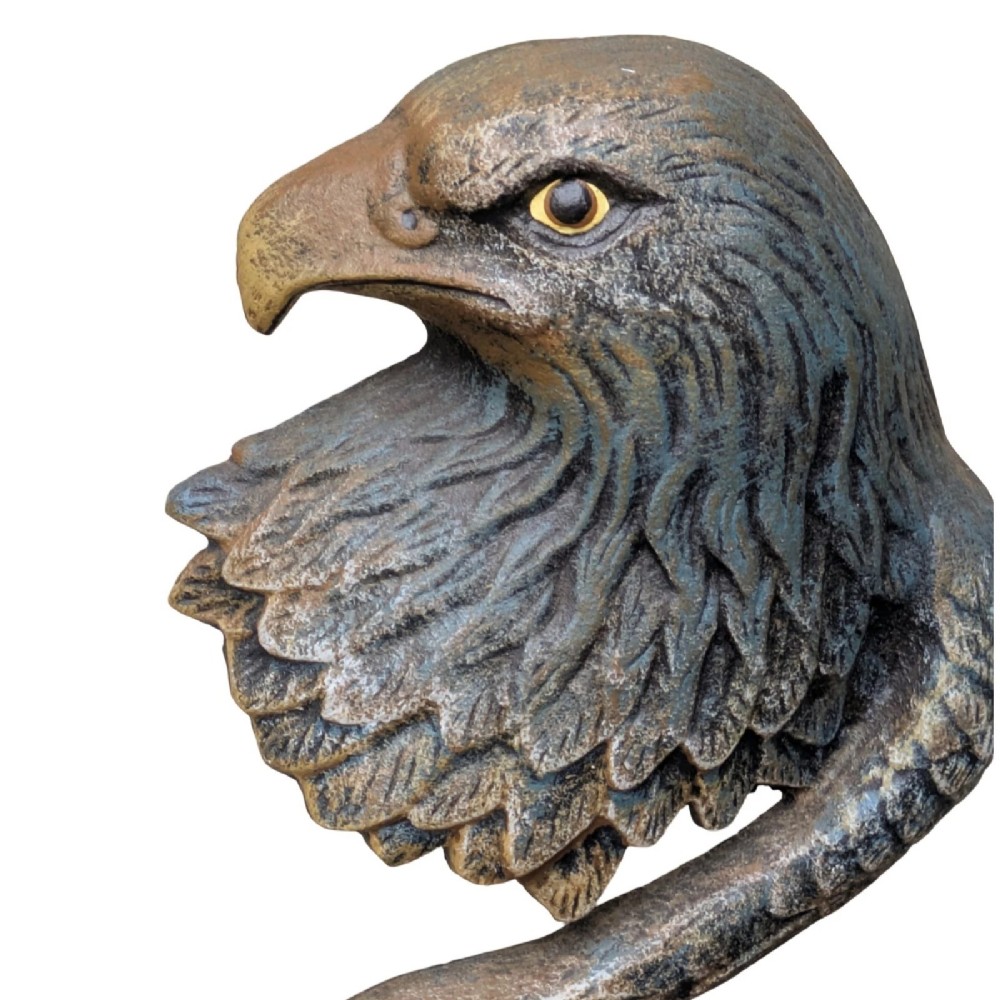 A cast iron doorstop styled as a sculpted eagle head resting on a stylized curved feather base set upon a round plinth. View II