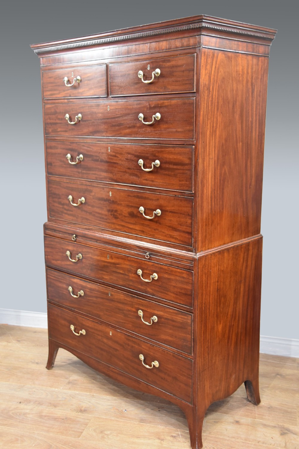 A Georgian mahogany chest on chest featuring two stacked drawer sections, brass swan-neck handles, a dentil cornice, and splayed bracket feet. View II