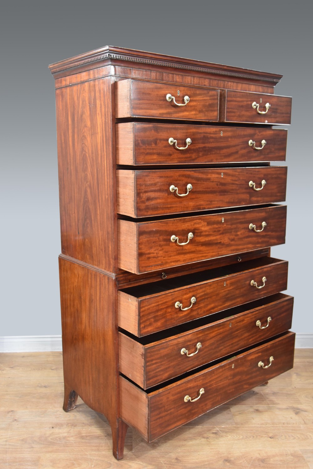 A Georgian mahogany chest on chest featuring two stacked drawer sections, brass swan-neck handles, a dentil cornice, and splayed bracket feet. View IV
