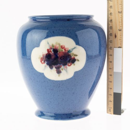 fig 2. A rounded ceramic vase featuring a mottled blue ground and a central white cloud-shaped reserve with hand-painted red and blue floral motifs.