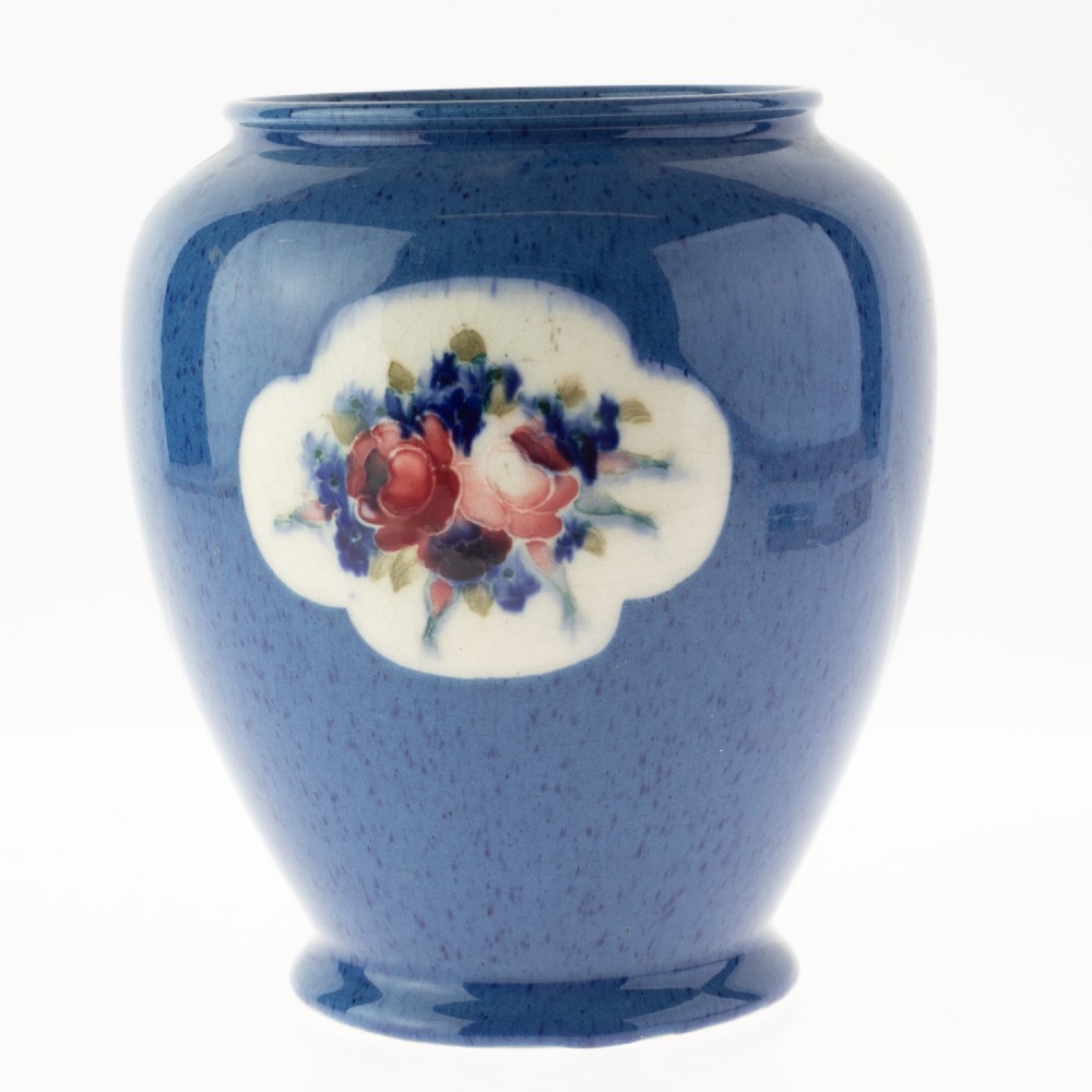 A rounded ceramic vase featuring a mottled blue ground and a central white cloud-shaped reserve with hand-painted red and blue floral motifs.