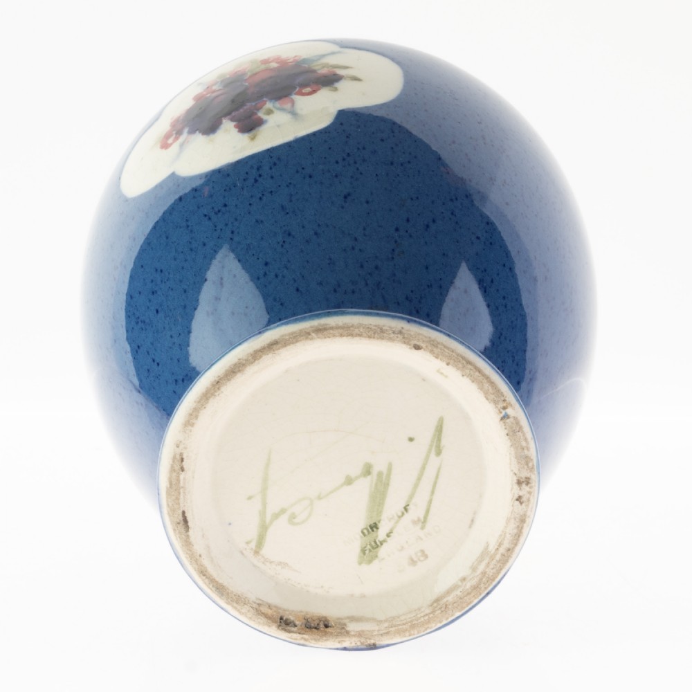 A rounded ceramic vase featuring a mottled blue ground and a central white cloud-shaped reserve with hand-painted red and blue floral motifs. View II