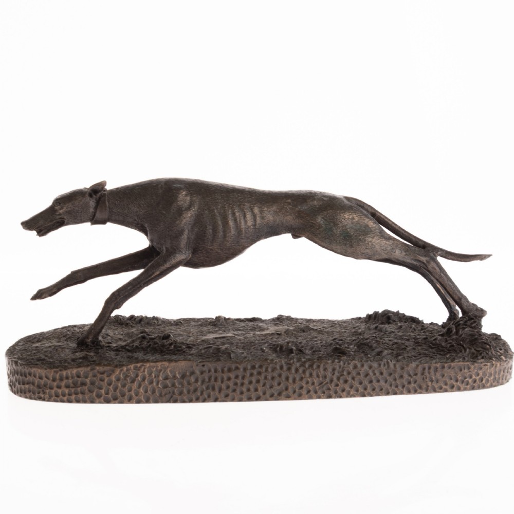 A dark patinated bronze sculpture capturing a greyhound in full stride mounted on a textured oval base.