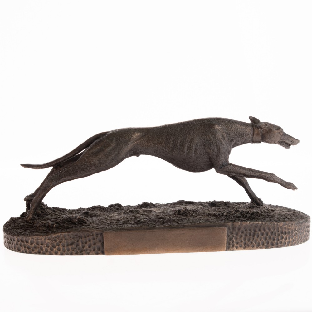 A dark patinated bronze sculpture capturing a greyhound in full stride mounted on a textured oval base. View III