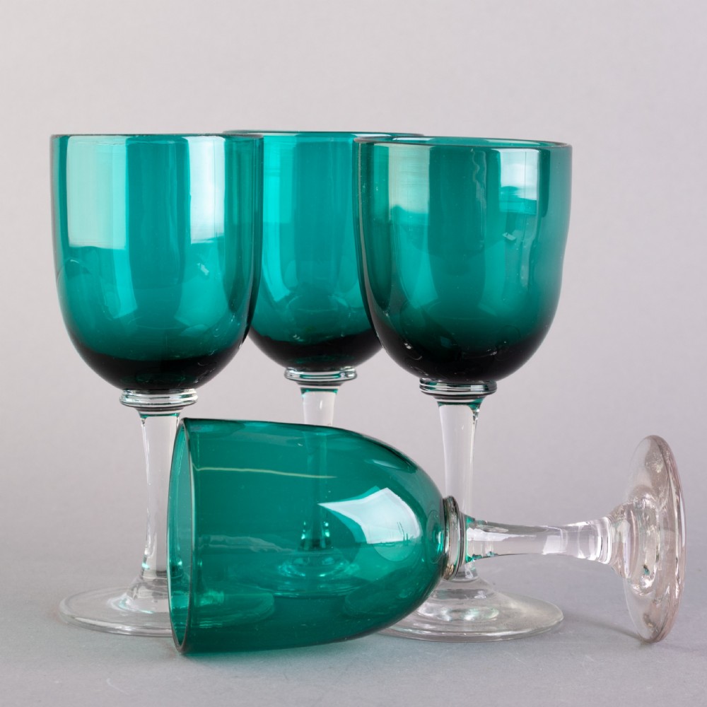 A set of four Victorian Bristol green glass wine goblets featuring clear stems and plain circular bases. View II