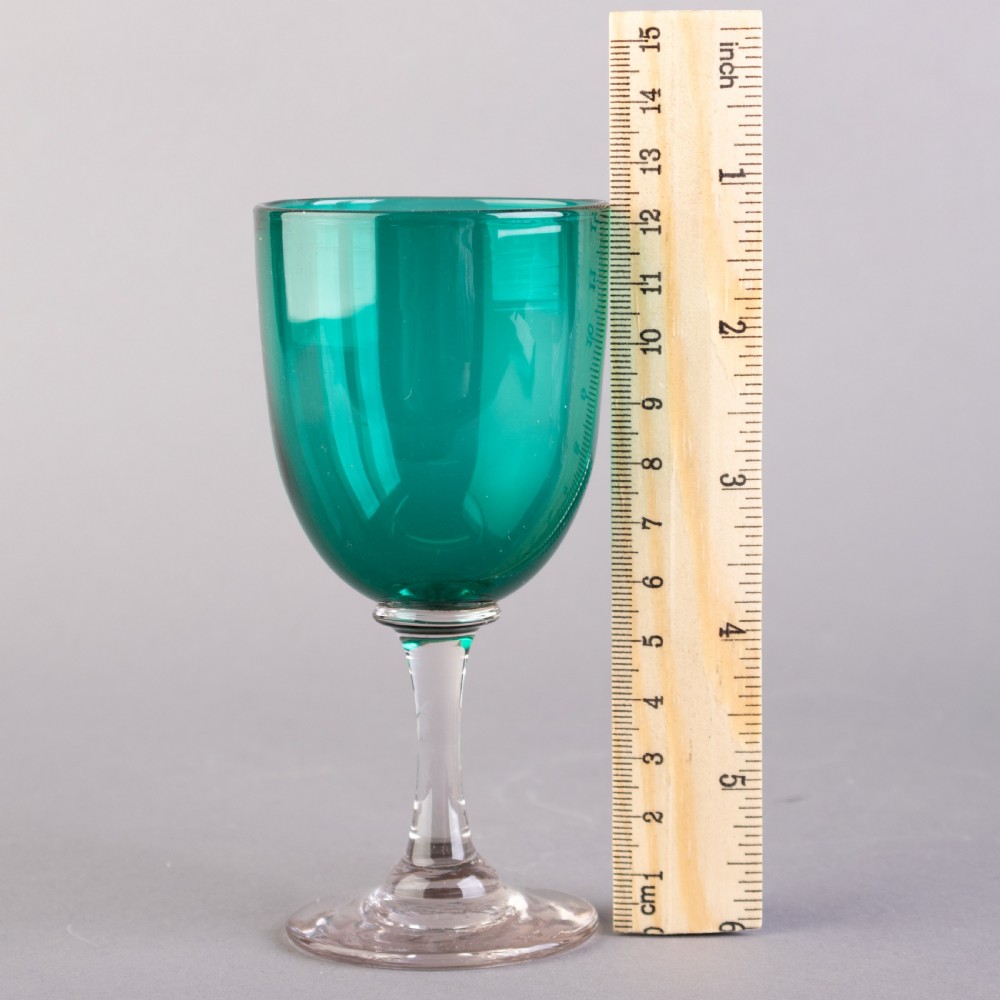 A set of four Victorian Bristol green glass wine goblets featuring clear stems and plain circular bases. View III