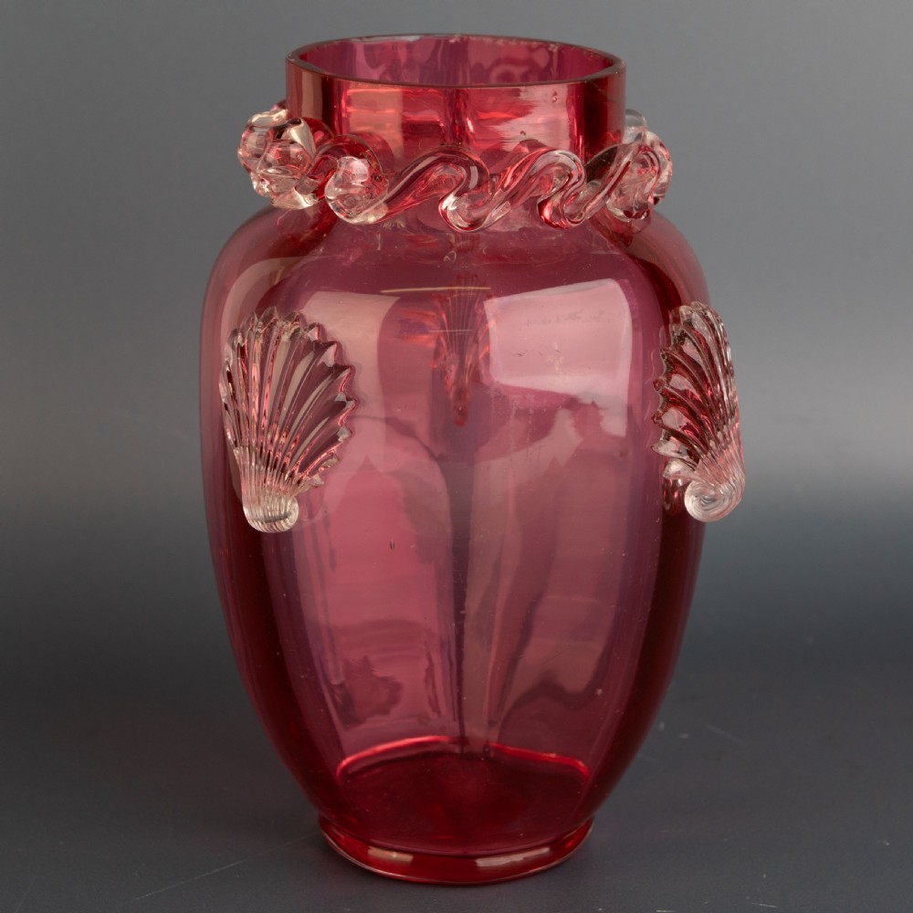 A Victorian hand-blown cranberry glass vase featuring an applied clear glass shell motif on the front and a crimped clear glass collar around the neck. View IV