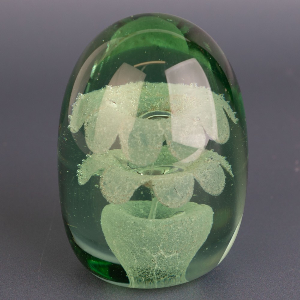 An ovoid green glass dump paperweight featuring trapped air bubble floral patterns inside a solid body. View III