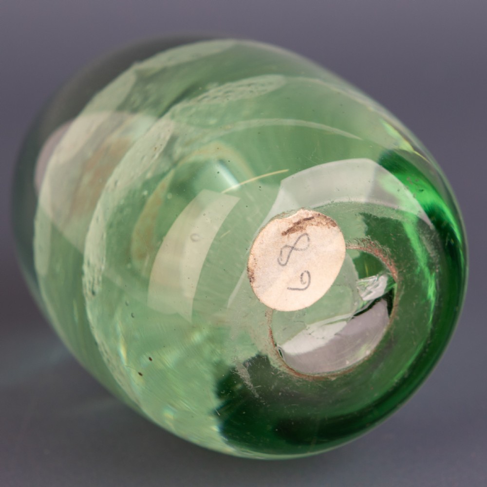 An ovoid green glass dump paperweight featuring trapped air bubble floral patterns inside a solid body. View V