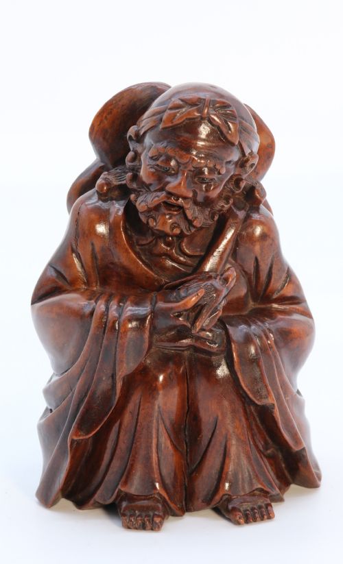 A Fine Japanese Carved Hardwood Mid 19th Century Okimono of a Seated Man Holding a Bat.