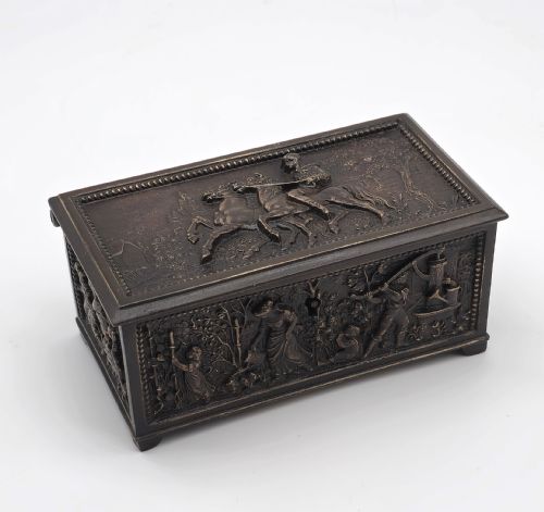 fig 1. A rectangular dark patinated bronze jewellery casket featuring raised relief scenes on the sides and lid, accompanied by a small decorative key.