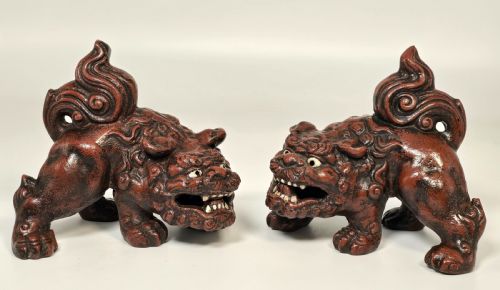 fig 1. A pair of reddish-brown cast iron Chinese guardian lion figures featuring raised tails and open mouths displaying white painted teeth.