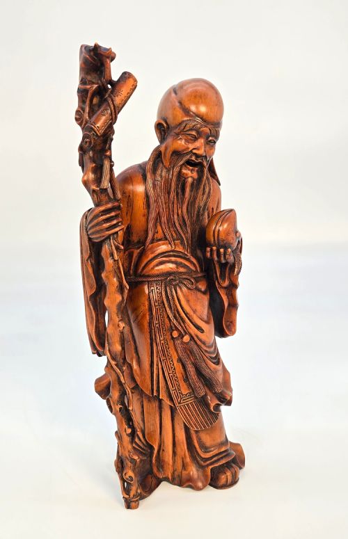 fig 1. A Japanese carved boxwood okimono figure depicting Fukurokuju with a high forehead, long beard, flowing robes, and holding a gnarled staff.