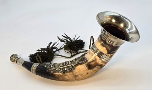 fig 1. A Victorian natural horn featuring silver-plated mounts, an engraved foliage crest with the letters AOF, and dark braided tassels.