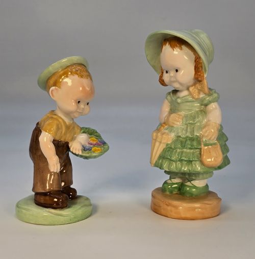 fig 1. A pair of 1930s Shelley porcelain figures designed by Mabel Lucie Attwell, depicting a boy in brown dungarees with a flower basket alongside a girl in a green bonnet and ruffled dress.