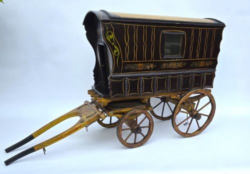 fig 1. An antique hand-painted wooden model of a Romani gypsy caravan vardo with yellow spoked wheels and floral detail.