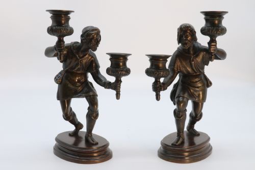 fig 1. A pair of 19th-century patinated dark bronze double candlesticks featuring sculpted male figures standing on oval bases and holding two sconces each.