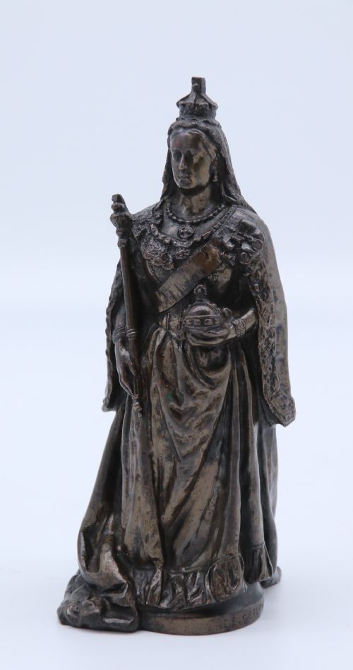 fig 1. A dark patinated bronze statuette depicting Queen Victoria standing in full ceremonial robes, wearing a crown and holding a sceptre and orb.