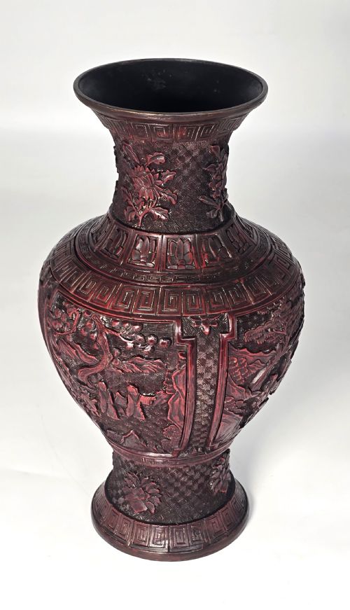 fig 1. A baluster-shaped red cinnabar lacquer vase decorated with relief carvings of figures in a landscape surrounded by floral and geometric borders.