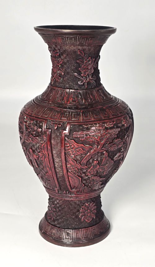 fig 2. A baluster-shaped red cinnabar lacquer vase decorated with relief carvings of figures in a landscape surrounded by floral and geometric borders.